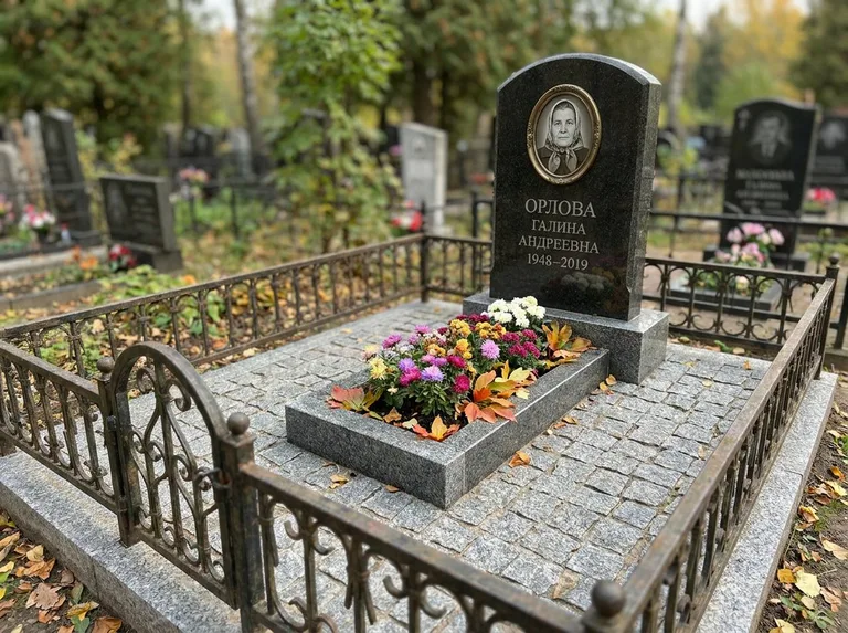 Благоустроенное захоронение с гранитной плиткой, оградой и цветником в Тюмени