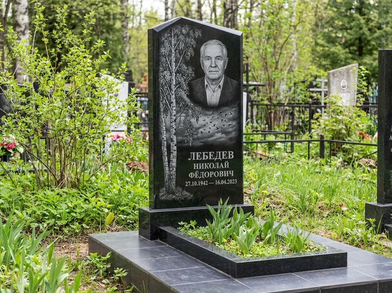 Памятник с гравировкой берёзы: вертикальная стела со скошенным верхом — берёза и стая птиц в небе, гранитный цоколь с тёмной плиткой, работа «Лебедев» в Тюмени
