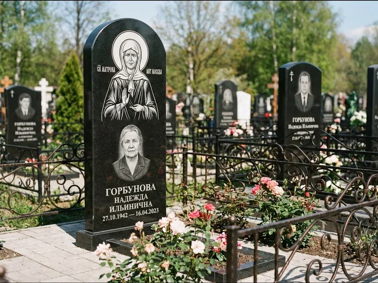 Памятник с гравировкой иконы: стела с арочным верхом и киотом под образ — гравировка образа Матроны Московской, гранитный цоколь с тёмной плиткой, работа «Ковалёв» в Тюмени