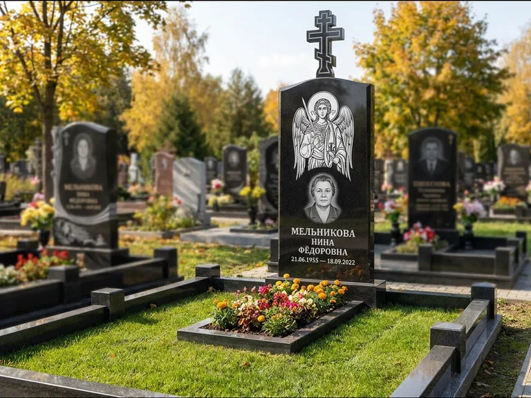 Памятник с гравировкой иконы: округлая стела-медальон с ликом — гравировка Богородицы «Семистрельная», луговые травы и полевые цветы за участком, работа «Гущин» в Тюмени