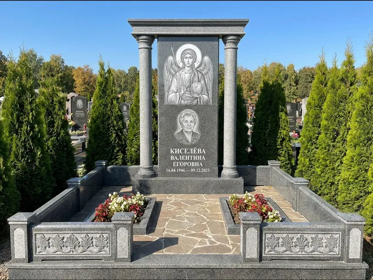 Памятник с гравировкой иконы: массивная стела с двускатным навершием-домиком — гравировка Николая Чудотворца, живая изгородь из туи, работа «Журавлёв» в Тюмени