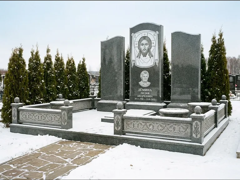 Памятник с гравировкой иконы: узкая вертикальная стела-пилон с ликом — икона в резной рамке-киоте, открытая лужайка без ограды, работа «Одинцов» в Тюмени