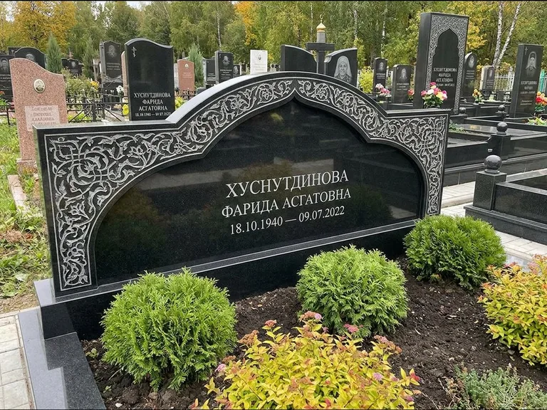 Мусульманский памятник: вытянутая горизонтальная семейная стела с аркой — белая гравировка силуэта мечети с минаретами, участок с декоративными кустами, работа «Зарипова» в Тюмени