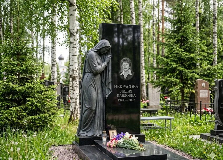 Гранитная фигура скорбящего мужчины у чёрной стелы в Тюмени